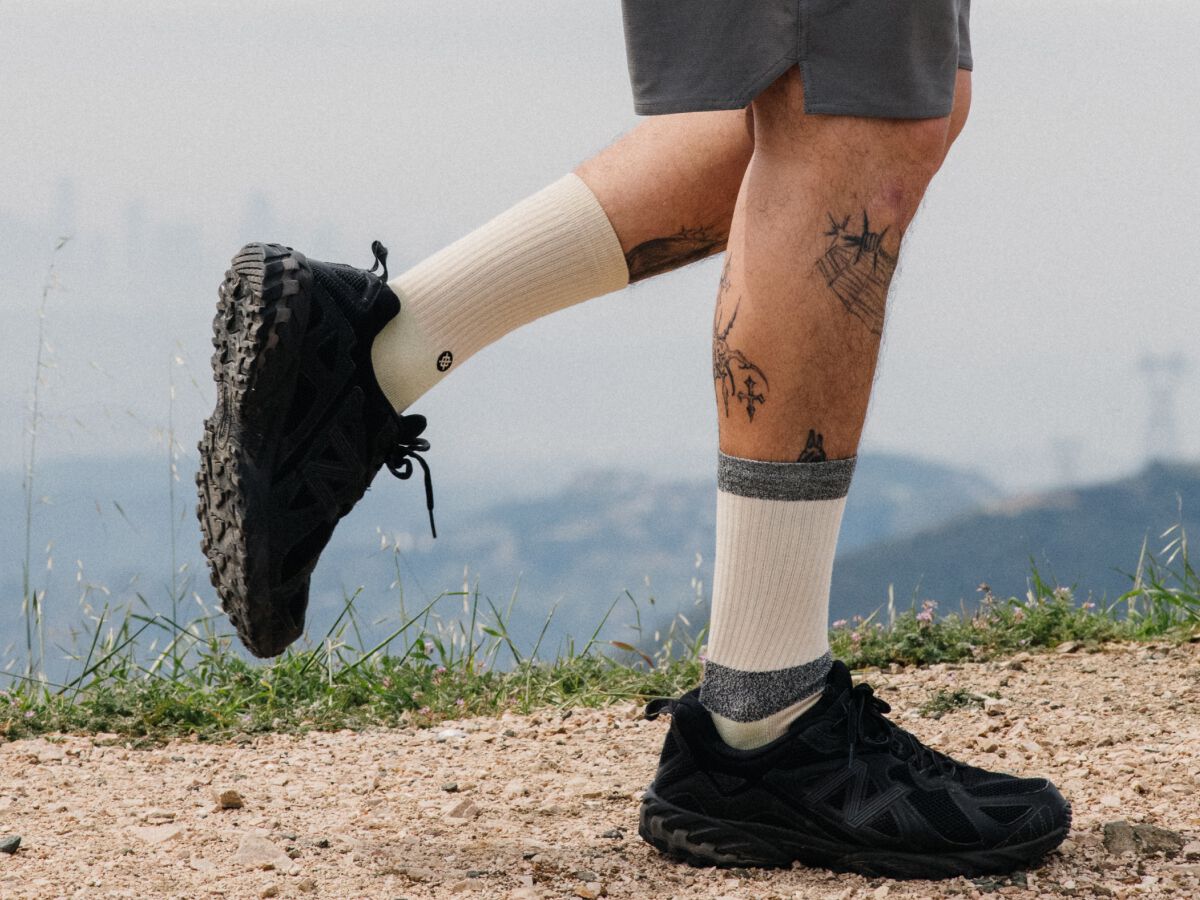 photo of a model walking on a dirt path wearing butter blend crew socks.